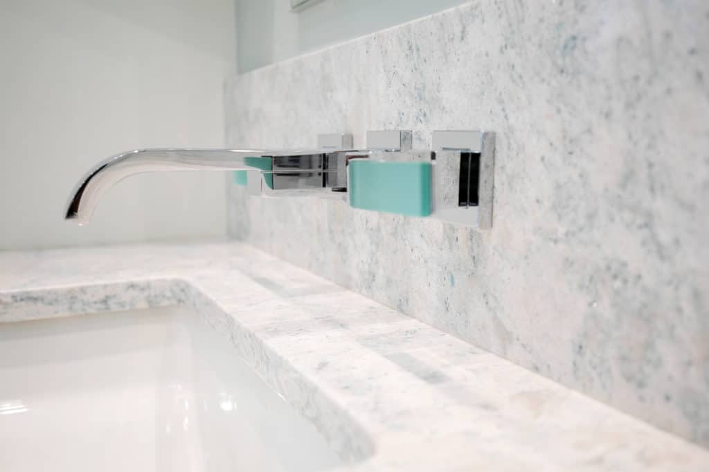 bathroom remodeling - An image of a bathroom sink with a silver faucet and marble backsplash. 