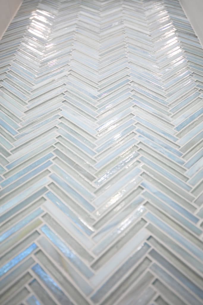 Blue and grey narrow flooring tiles laid out in a repeating chevron pattern 