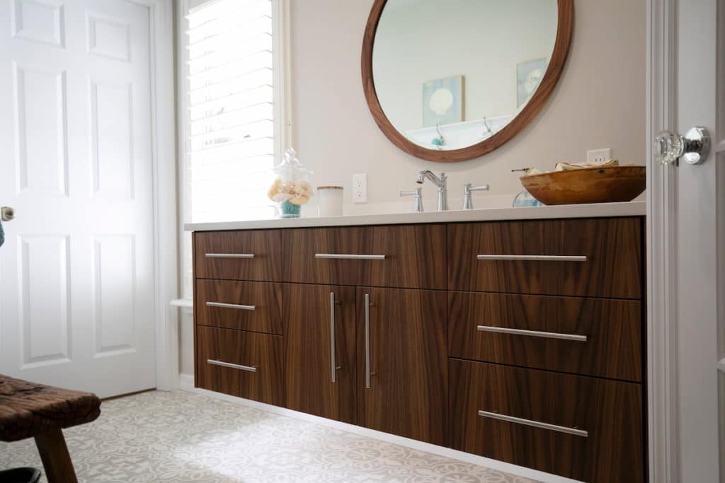 Well lit modern bathroom with large circular mirror, off-white walls and an oak vanity 