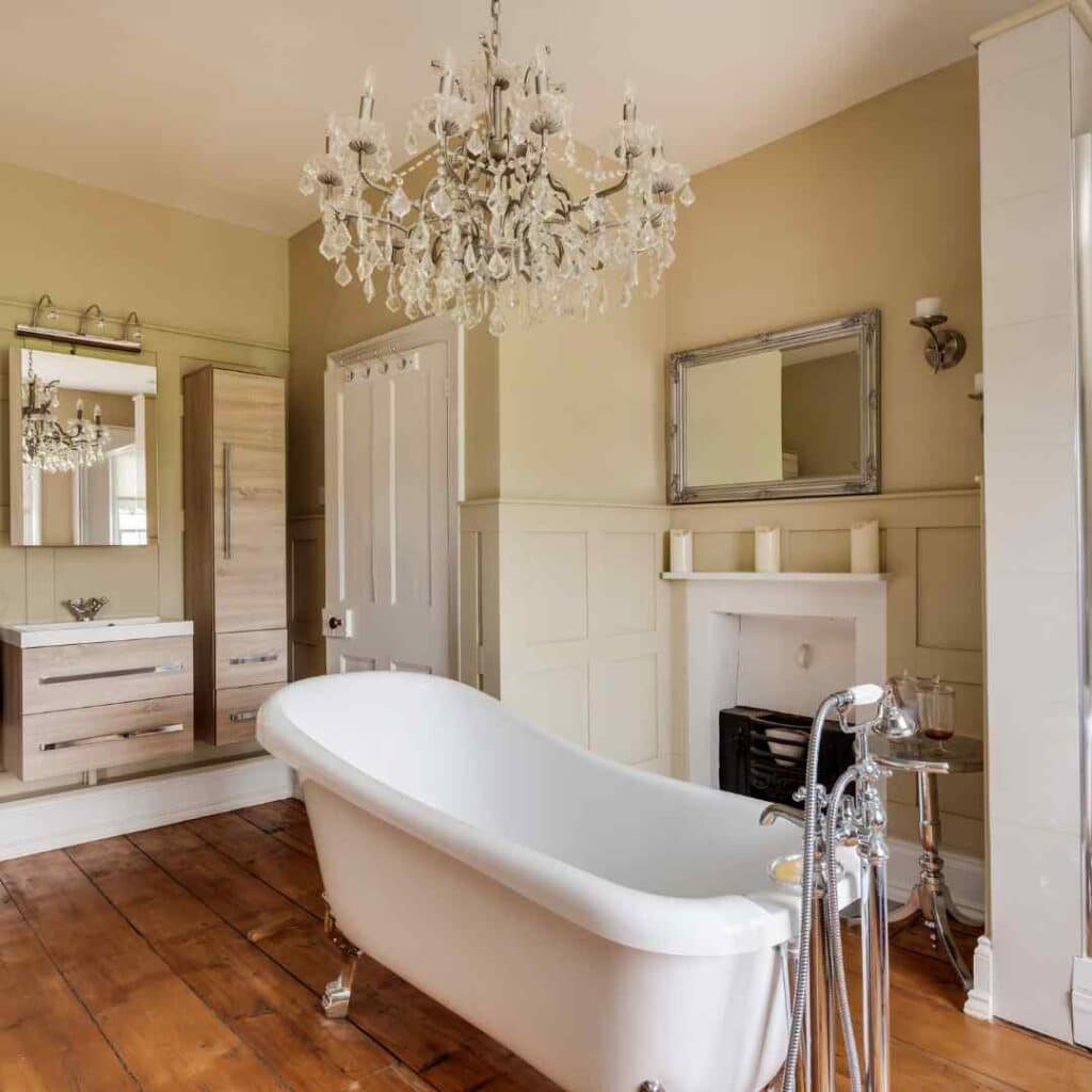 A clawfoot tub in a bathroom with a chandelier hanging over it