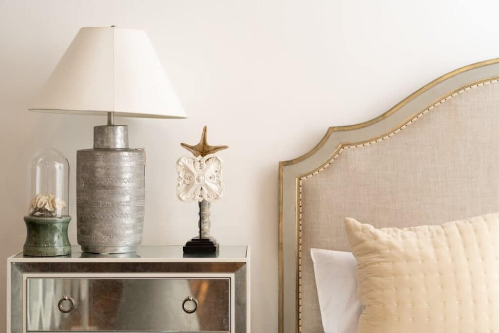 Close up of a coastal theme bedroom with shells on nightstand and bohemian metallic lamp 