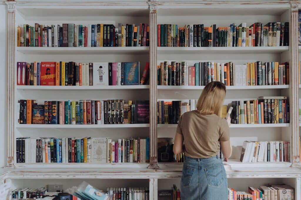 Woman looking at a range of books on a vintage/distressed built in bookcase 