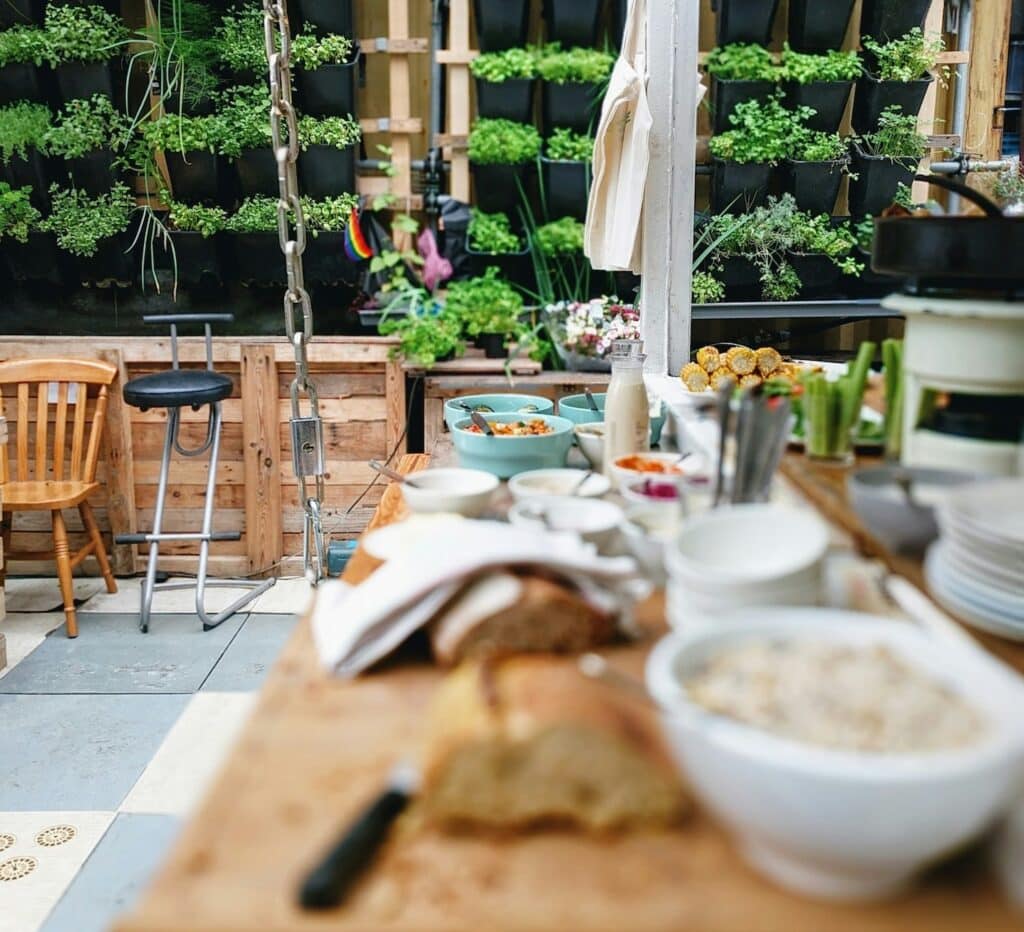 Sustainable outdoor kitchen space with a wall full of plants and rustic reclaimed wood walls 

